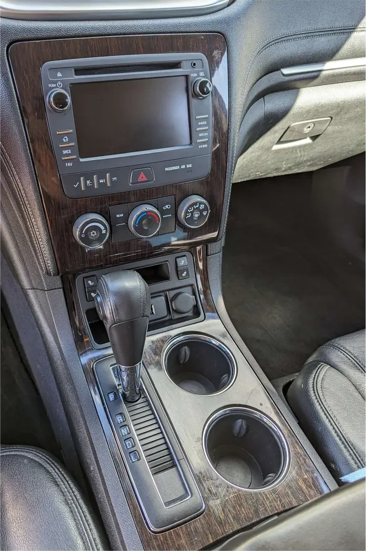 The same console after: wood trim wiped clean, cupholders emptied and cleaned, screen and controls dust-free