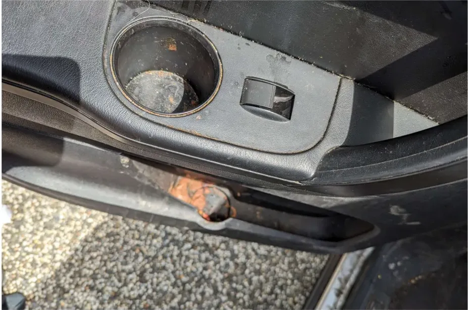 A rear door cupholder before detailing: sticky residue and rust-colored stains in and around the cup