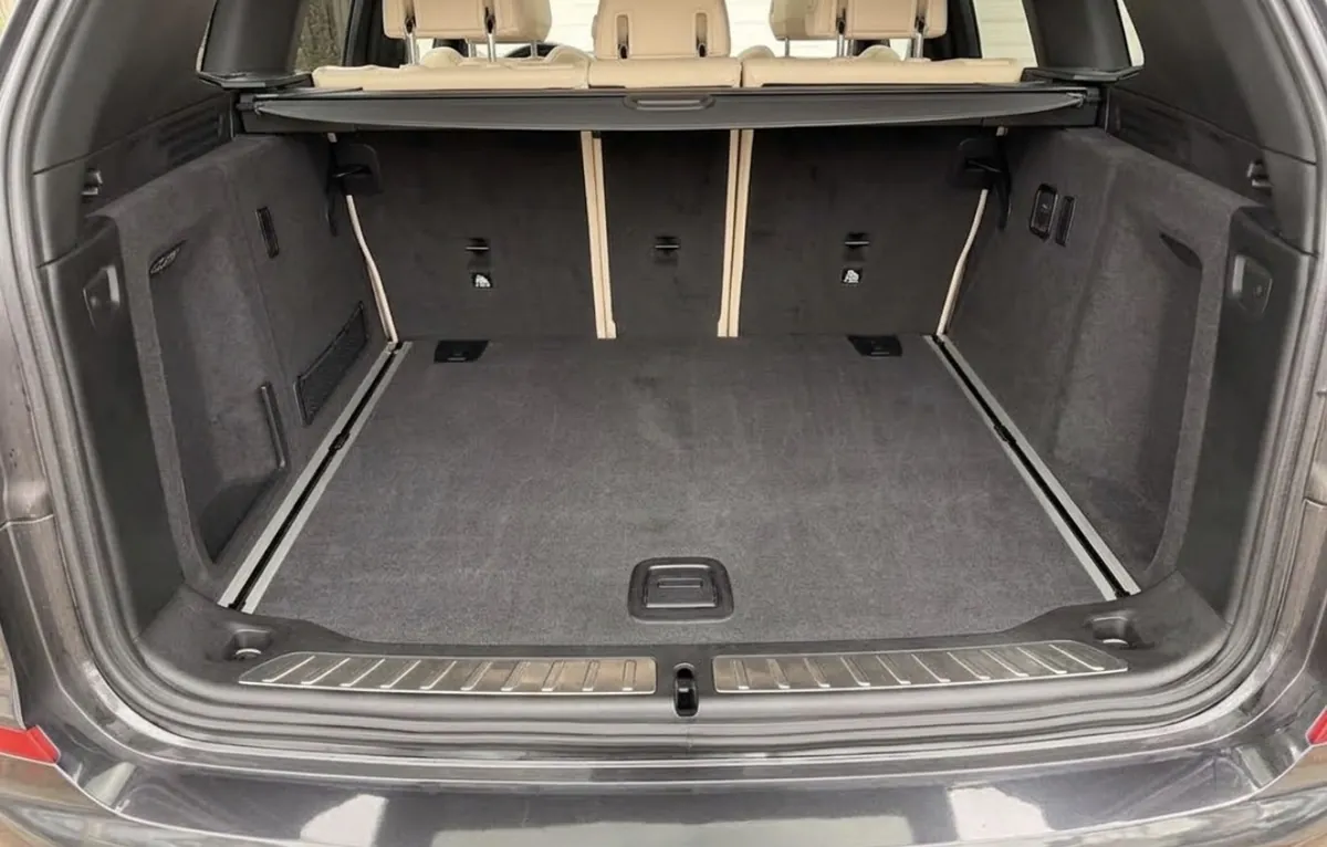The cargo area of a BMW X3 after a deep clean: carpet extracted, side panels and sill plate wiped down