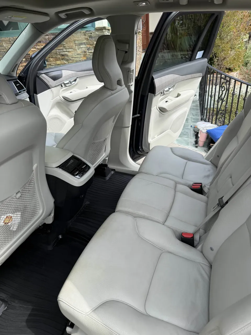The rear bench of the Volvo after detailing: light leather seats and door panels wiped down, black floor liners clean